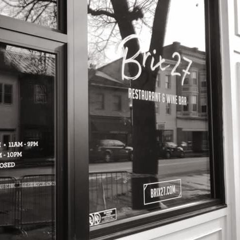 Brix27 restaurant and wine bar window display featuring business hours and website, showcasing modern signage and street view.