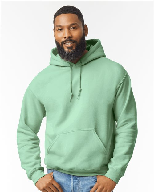 Man wearing a mint green Gildan Heavy Blend&trade; hooded sweatshirt, showcasing a casual style.